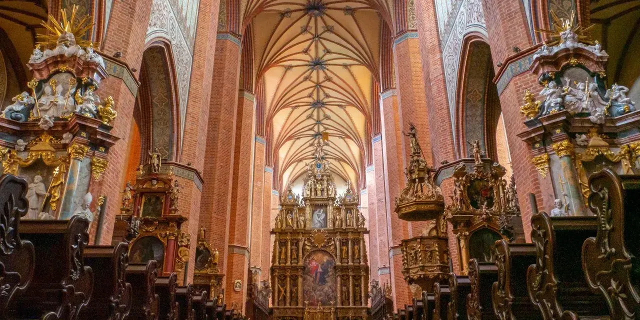 Wnętrze katedry w Pelplinie, z bogato zdobionym ołtarzem i rzędami drewnianych ławek. To jedna z głównych atrakcji Pelplina.