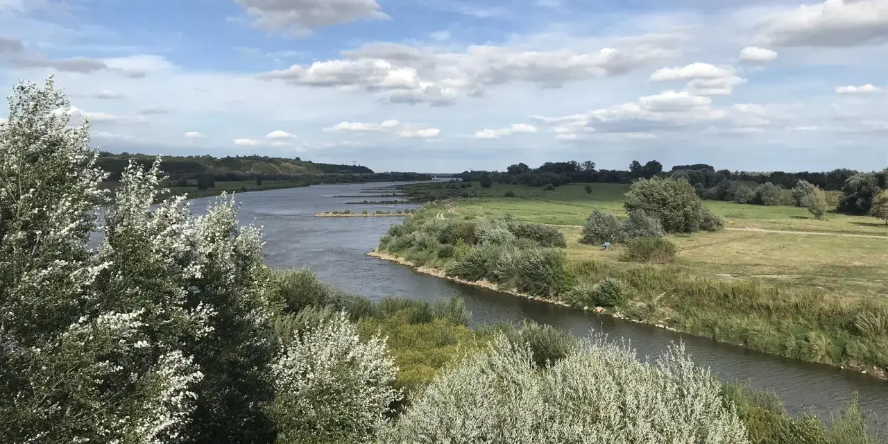 Malowniczy krajobraz z rzeką i zielonymi wzgórzami, idealny na sandomierz trasy rowerowe.