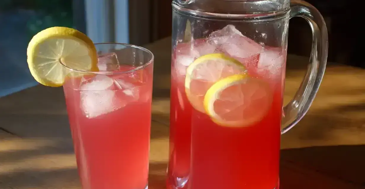 En karaff och ett glas med rosa lemonad, is och citronskivor. Perfekt för ett enkelt lemonad recept.