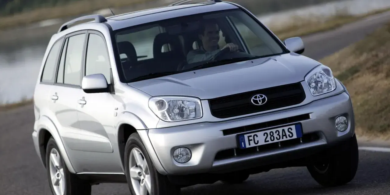 Srebrny SUV Toyota RAV4 na drodze, z kierowcą za kierownicą.