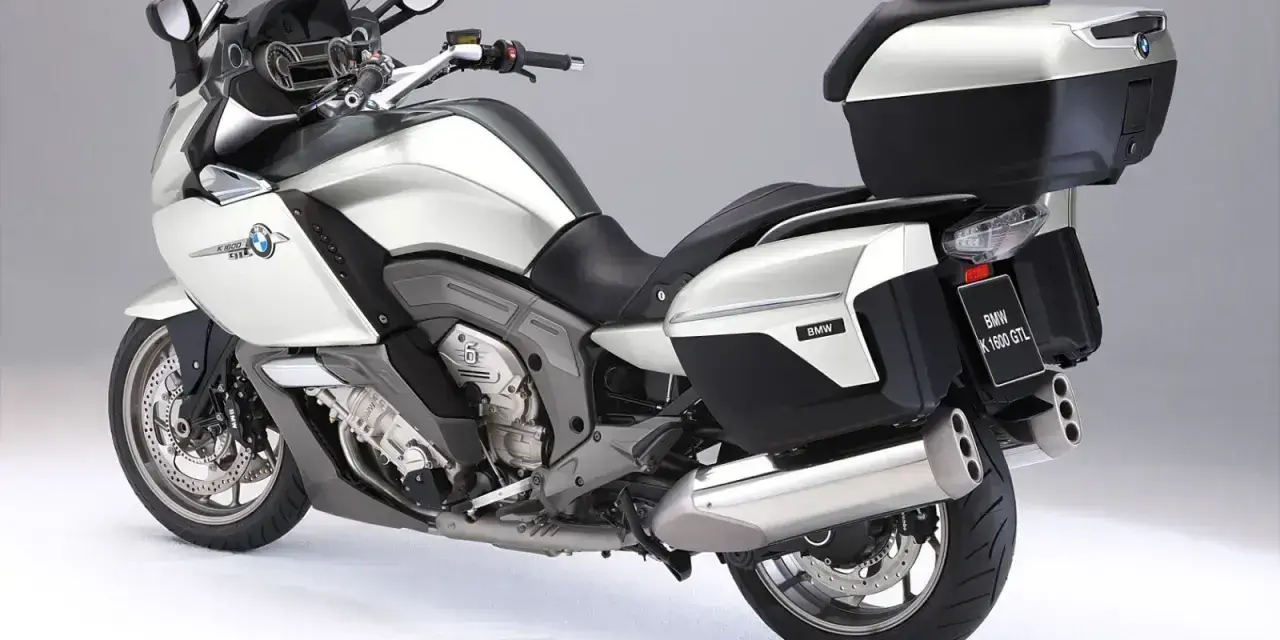 Srebrny motocykl BMW K1600GTL z kuframi i podnóżkami. Idealny do długich podróży, sprawdź jego bmw k1600gtl dane techniczne.