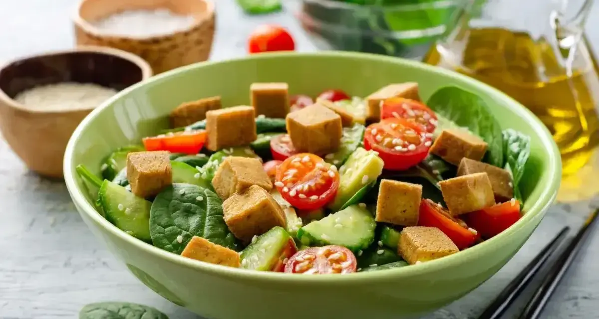Kolorowa sałatka z chrupiącym tofu, pomidorkami koktajlowymi i ogórkiem na świeżym szpinaku.