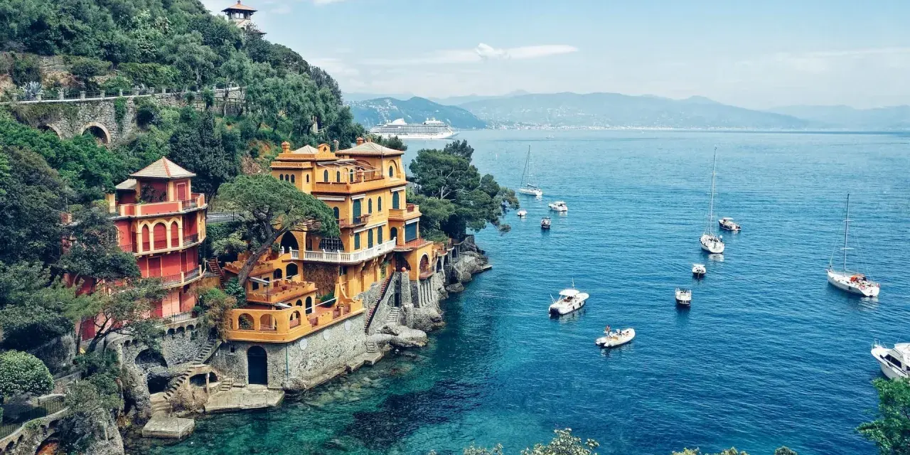 Bunte Häuser am Hang über dem türkisfarbenen Meer, Boote schaukeln im Wasser. Ein Traumziel für jeden Campingplatz Italien!