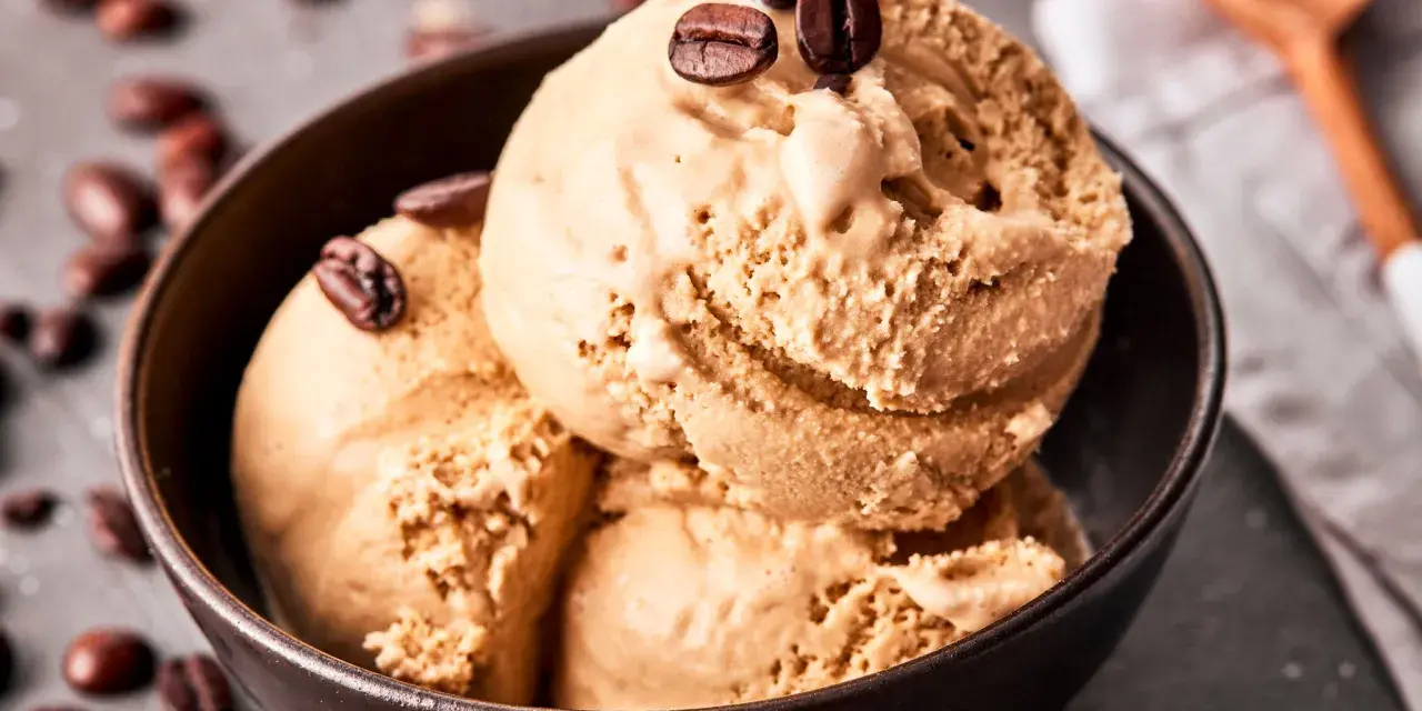 Kaffee Eis in einer Schale, garniert mit Kaffeebohnen. Ein Löffel liegt daneben.
