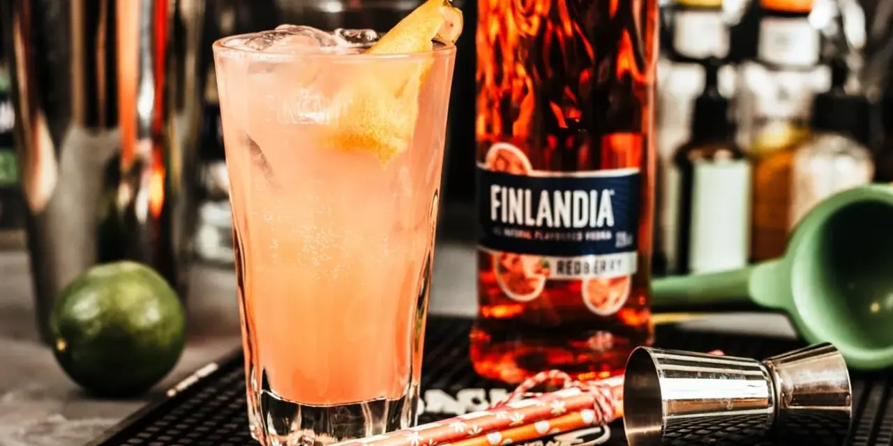 Orzeźwiające drinki z Finlandia Redberry, idealne na letnie wieczory. W szklance różowy koktajl z lodem i skórką cytrusową.