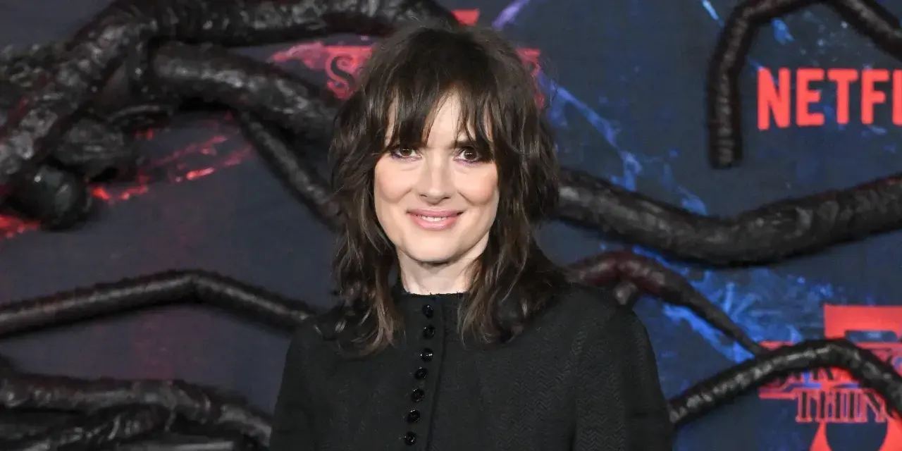 Winona Ryder, gwiazda filmów i seriali, w tym "Stranger Things", na tle dekoracji z mackami i logo Netflix.