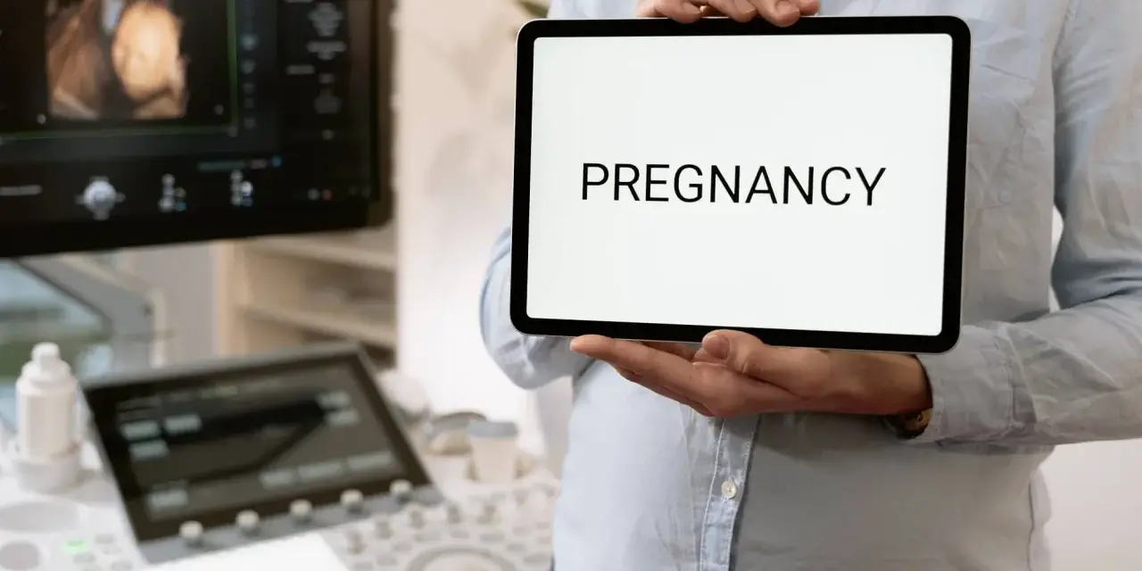 Wczesna ciąża, 2 tydzień. USG pokazuje zarodek, a na tablecie widnieje napis "PREGNANCY".