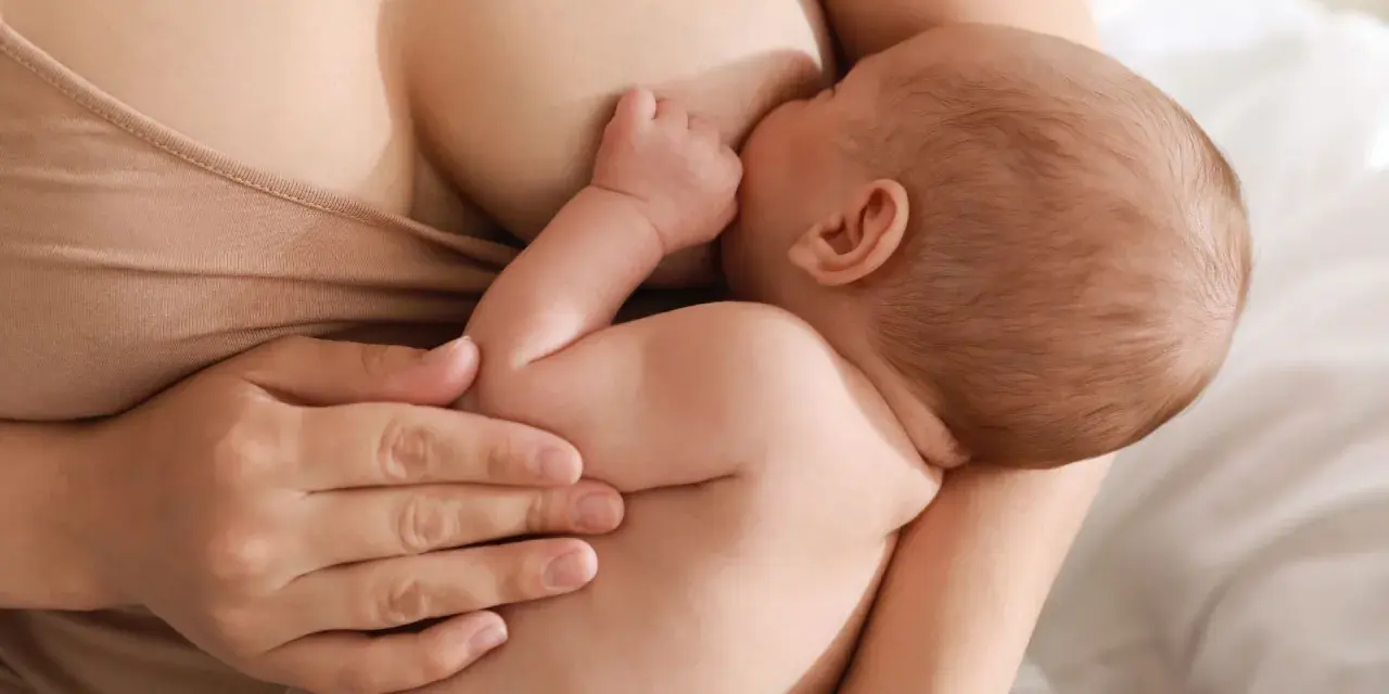 Un neonato si nutre al seno, ricevendo il prezioso colostro, un dono naturale per la sua crescita.