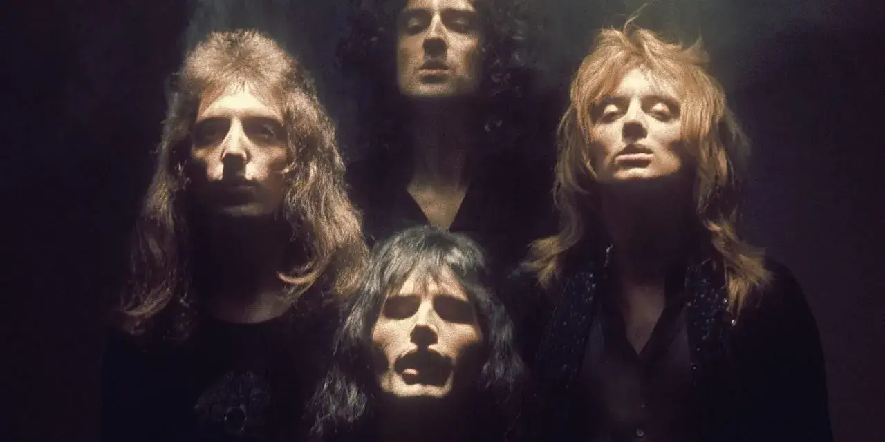 Czterech członków zespołu Queen w mrocznym klimacie, jakby przygotowujących się do wykonania "Bohemian Rhapsody". Ich spojrzenia sugerują głęboką interpretację.