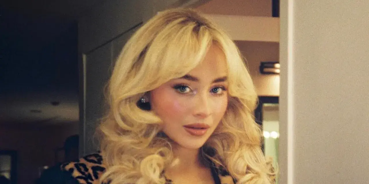 Frau mit voluminösem blondem Haar und Leopardenmuster-Jacke.