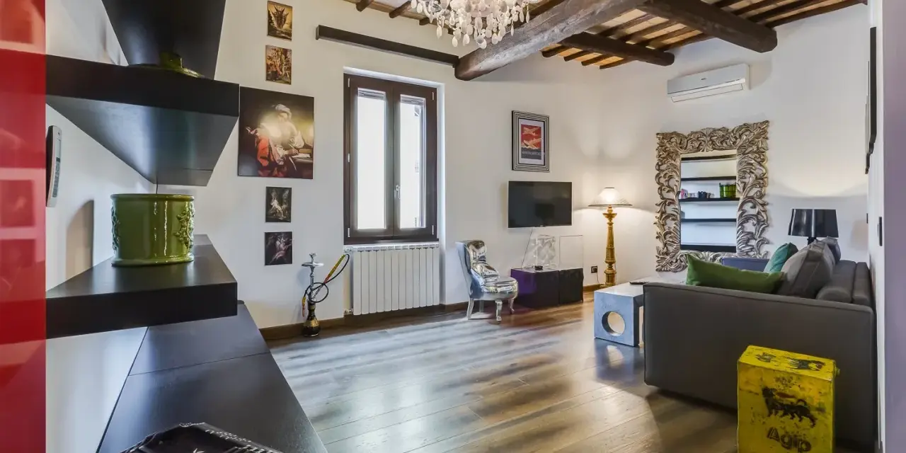 Soggiorno con travi a vista, lampadario di cristallo e un tocco di stile rustico.