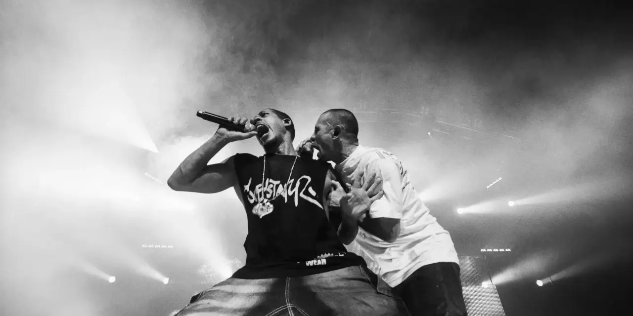 Deux rappeurs en pleine performance, l'un tenant un micro, l'autre le soutenant. Une scène intense qui illustre la puissance du hip hop en France.