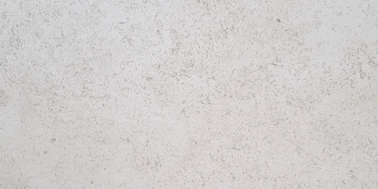 Surface texturée d'enduit chaux chanvre finition lisse, d'une teinte claire et naturelle, évoquant la douceur d'un mur sain.