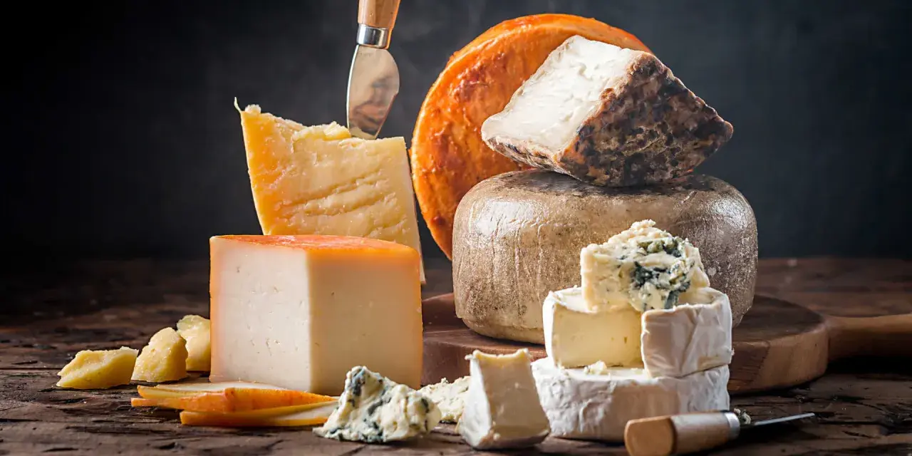 Kuski najlepsze sery: parmezan, pleśniowy, camembert i inne, ułożone na drewnianej desce.