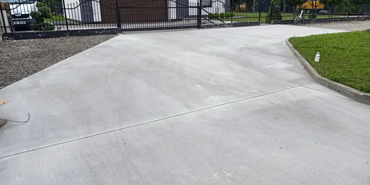 Nowy podjazd z betonu przed domem z garażem i bramą.