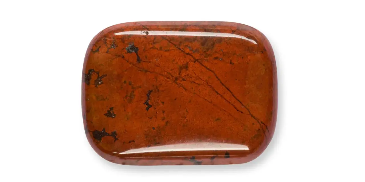 Una piedra de jaspe rojo pulido, con vetas oscuras y manchas, que muestra la belleza natural de que es el jaspe.