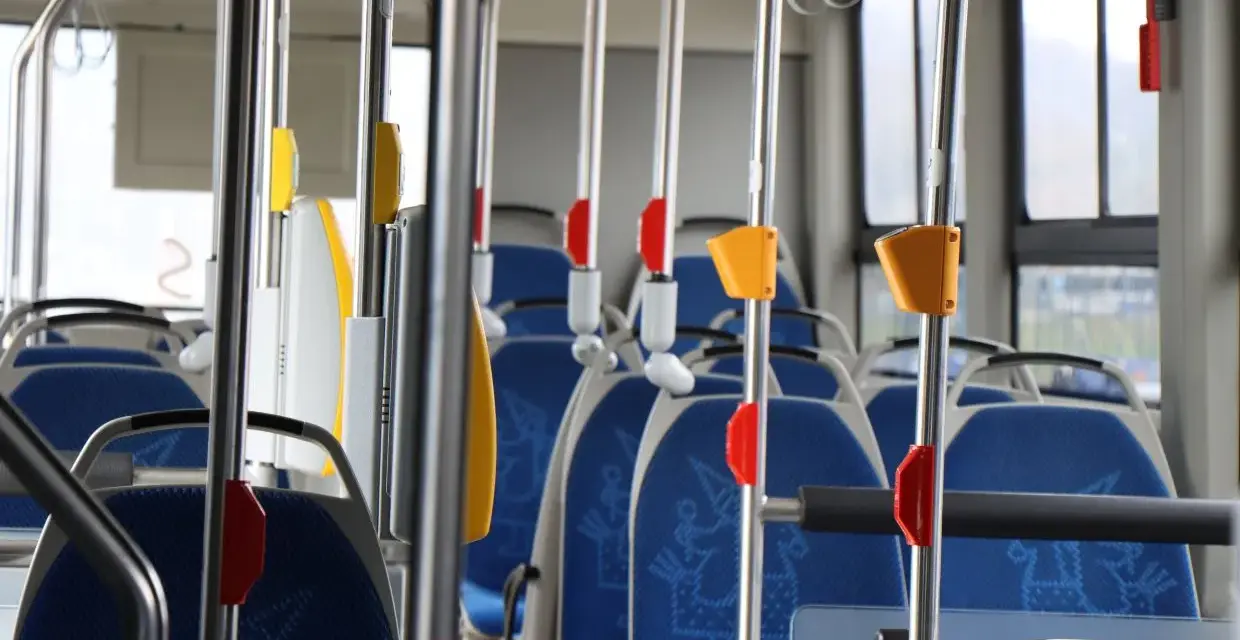 Wnętrze autobusu 139 z niebieskimi siedzeniami i metalowymi poręczami.