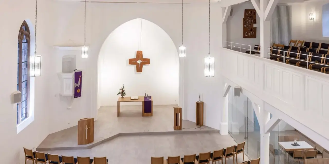 Moderner Aufbau evangelische Kirche mit Holzkreuz, Altar, Kanzel und vielen Sitzplätzen.