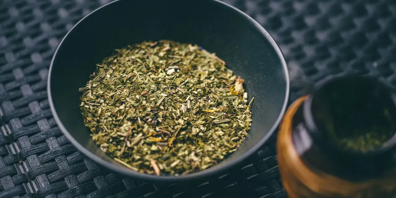 Suszone liście yerba mate w czarnej miseczce, gotowe do zaparzenia. To naturalny napój pobudzający.