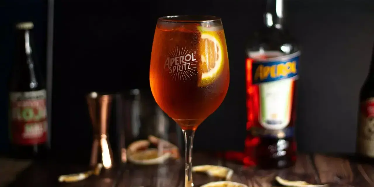 Orzeźwiający aperol z tonikiem, ozdobiony plasterkiem pomarańczy, gotowy do degustacji.