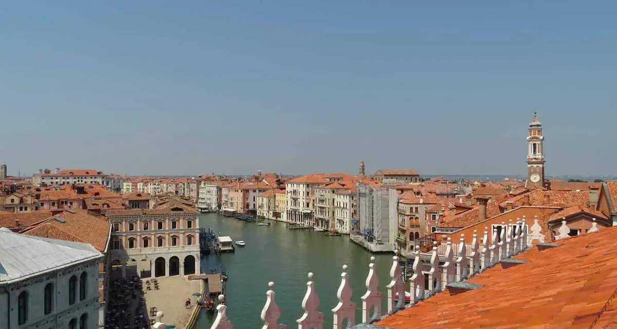 Vista dall'alto dei tetti rossi di Venezia, con il Canal Grande e le sue calli animate.