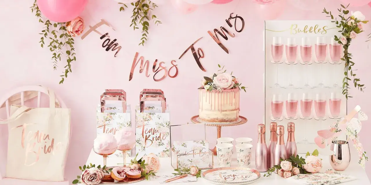 Uroczy wystrój na wieczór panieński: tort, balony, napisy "From Miss To Mrs", torby "Team Bride" i kieliszki z różowym napojem. Idealne pomysły, co robic na panieńskim!