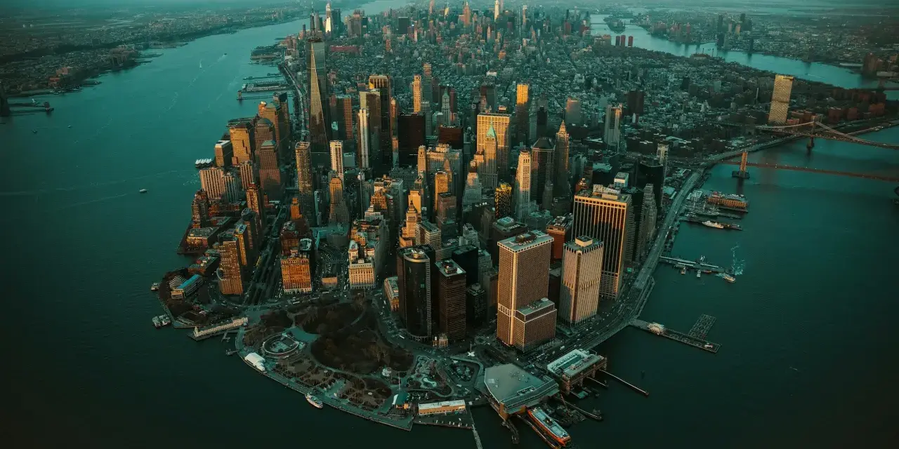 Zachód słońca nad Manhattanem, ta scena ukazuje panoramę drapaczy chmur i rzeki.
