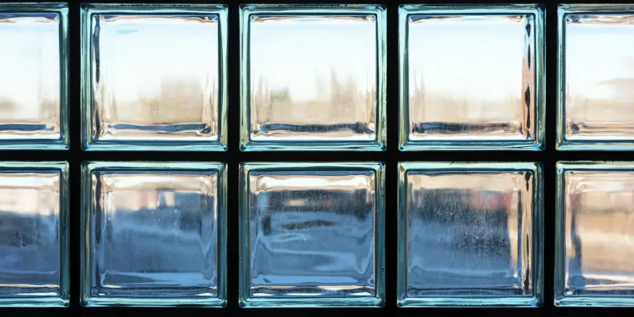 Un mur en brique de verre, reflétant la lumière extérieure, crée une ambiance douce et diffuse.