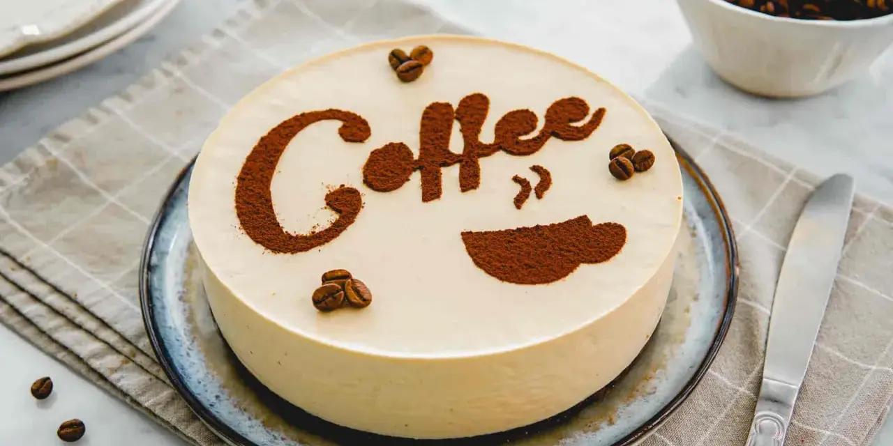 Deliziosa cheesecake al caffè, decorata con cacao e chicchi di caffè. Perfetta per gli amanti del gusto intenso.