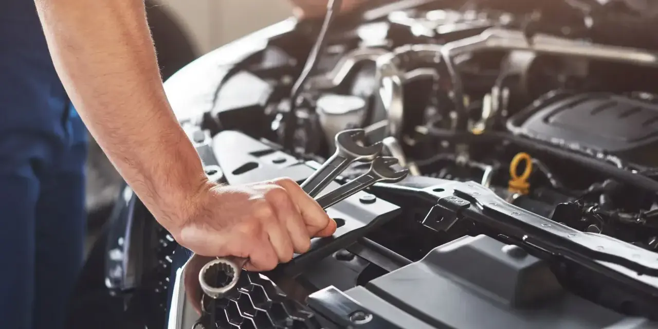 Mechanik sprawdza objawy awarii pompy paliwa Audi A4 B6 1.8T. W dłoni trzyma klucze.