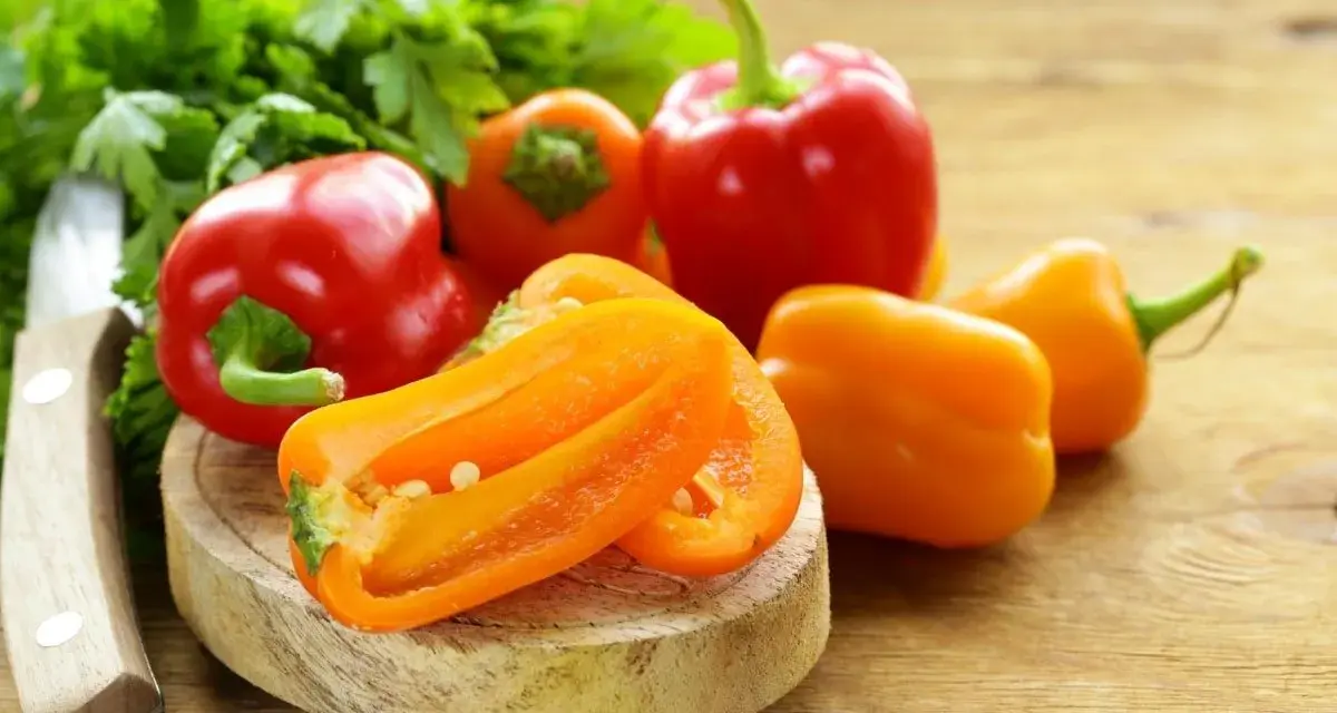 Peperoni piccoli colorati, pronti per gustose ricette. Un coltello e prezzemolo completano la scena.