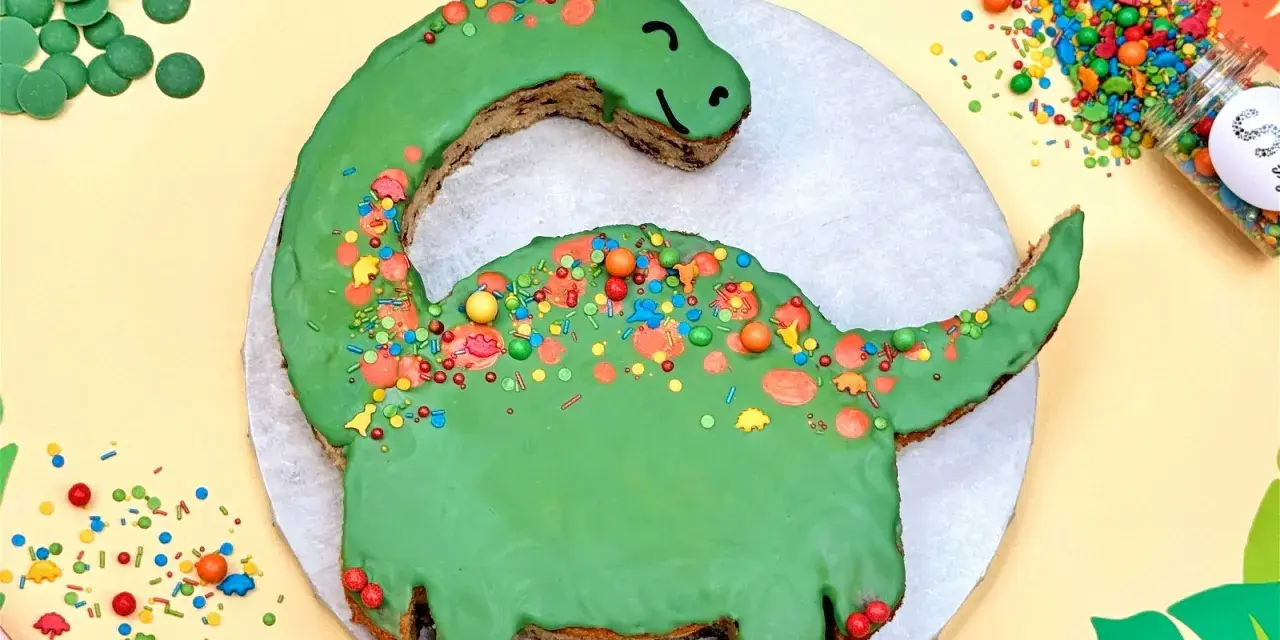 Grüne Dinosaurier Torte selber machen: Ein süßer Dino mit bunten Streuseln und Schokodrops. Perfekt für kleine Entdecker!