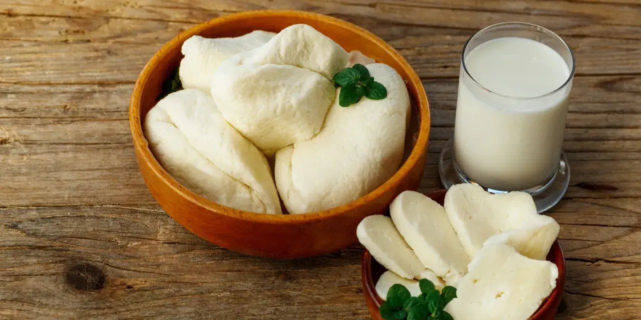 Ser halloumi w ciąży: świeży ser i szklanka mleka na drewnianym stole. Idealne dla przyszłej mamy.