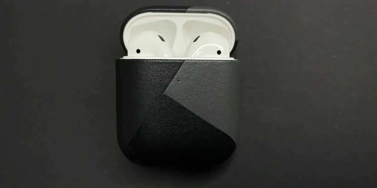 AirPods in einer schwarzen Hülle mit grauem geometrischem Muster.