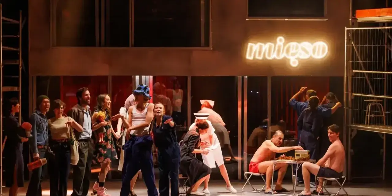 Scena z musicalu "1989". Aktorzy w strojach z epoki, neon "mięso" w tle.