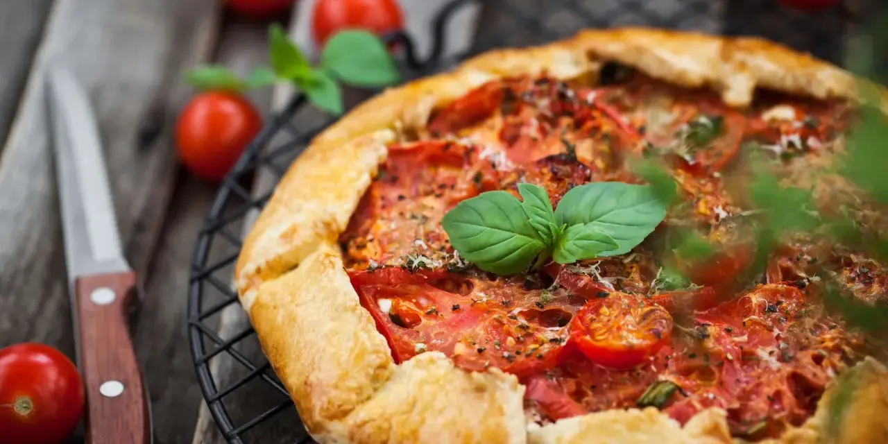 Torta salata con pomodorini freschi e basilico, pronta per essere gustata.