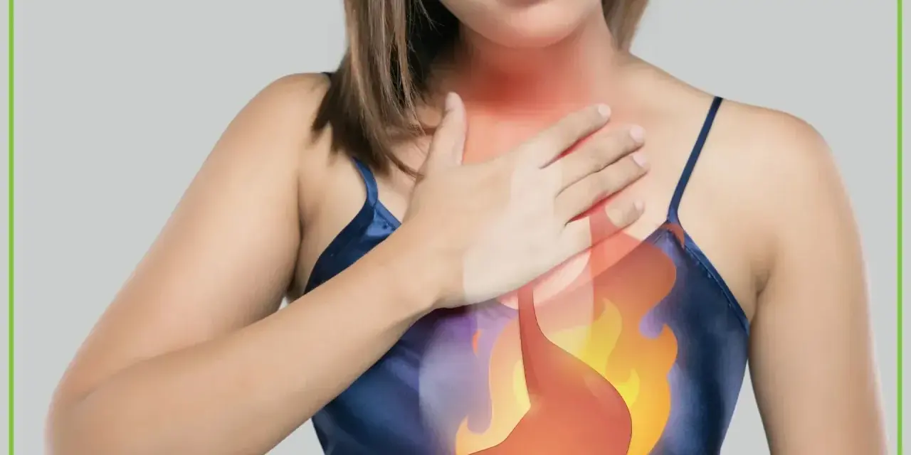 Kobieta trzyma się za klatkę piersiową, gdzie widoczna jest grafika płonącego żołądka. To wizualizacja, jak czuje się osoba z **zgagą od czego**ś.