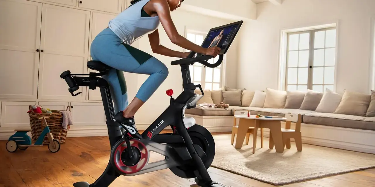 A woman rides a Peloton bike, a popular tool for peloton weight loss, in a bright, homey living room.