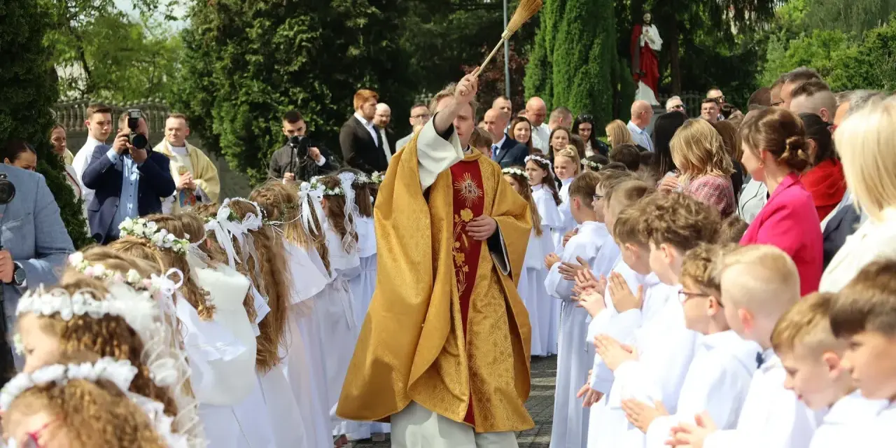 Uroczystość I Komunii Świętej. Dzieci w bieli, ksiądz błogosławi. Zastanawiasz się, ile kosztuje talerzyk na komunie?