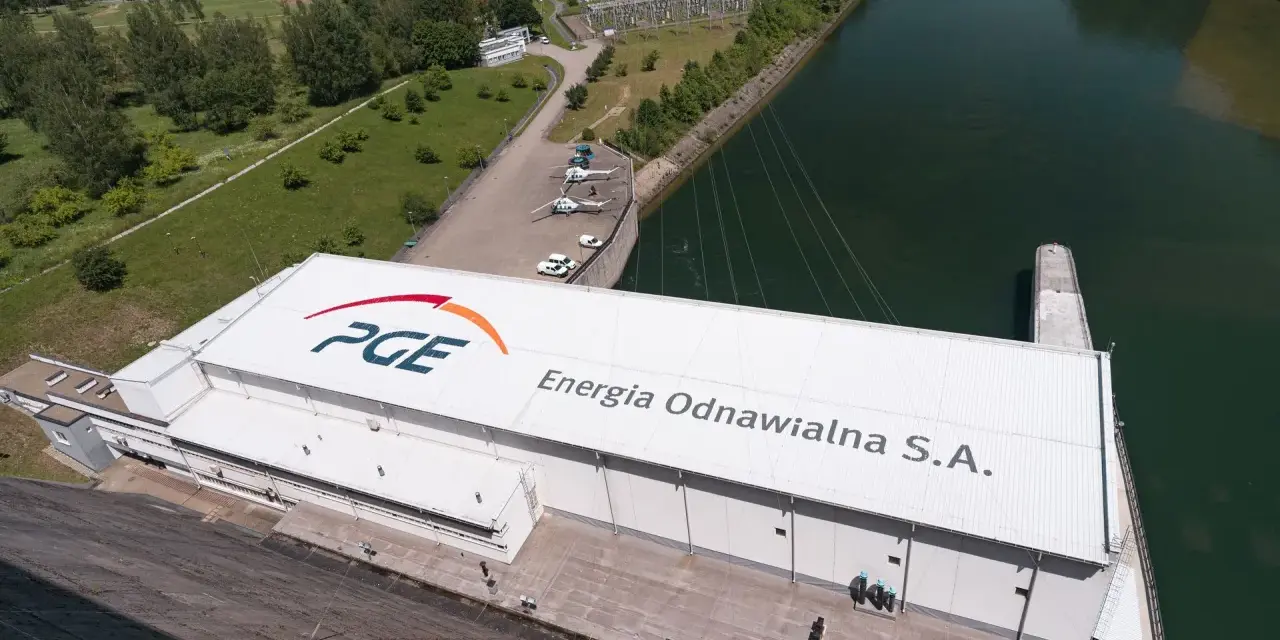 Widok z lotu ptaka na elektrownię wodną PGE Energia Odnawialna S.A. z charakterystycznym logo. Widać tam też helikoptery i samochody.