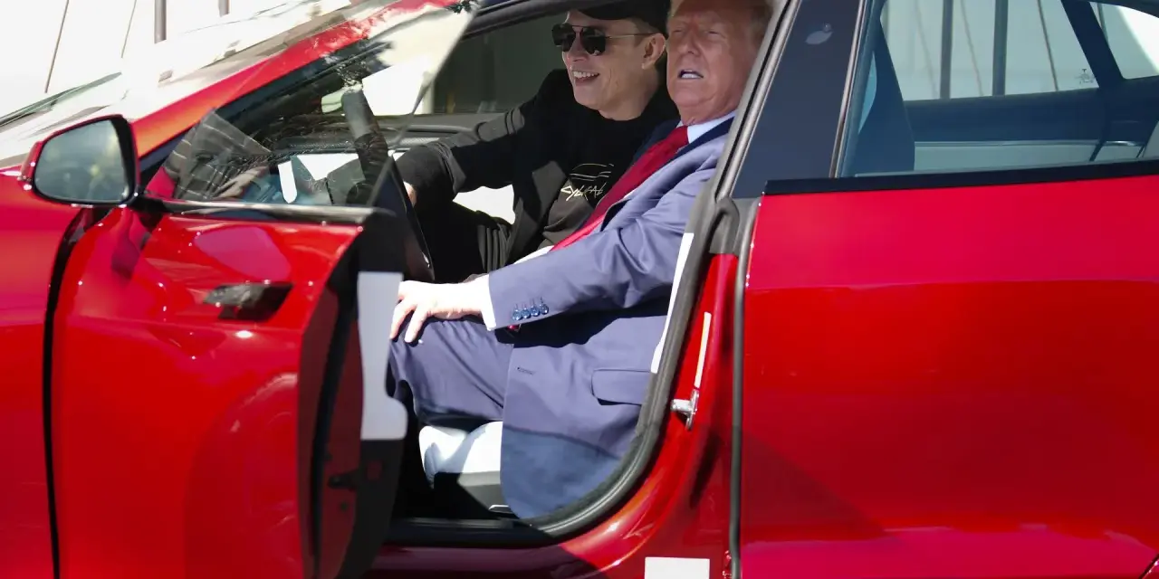 Elon Musk i Donald Trump siedzą w czerwonym samochodzie Tesla.