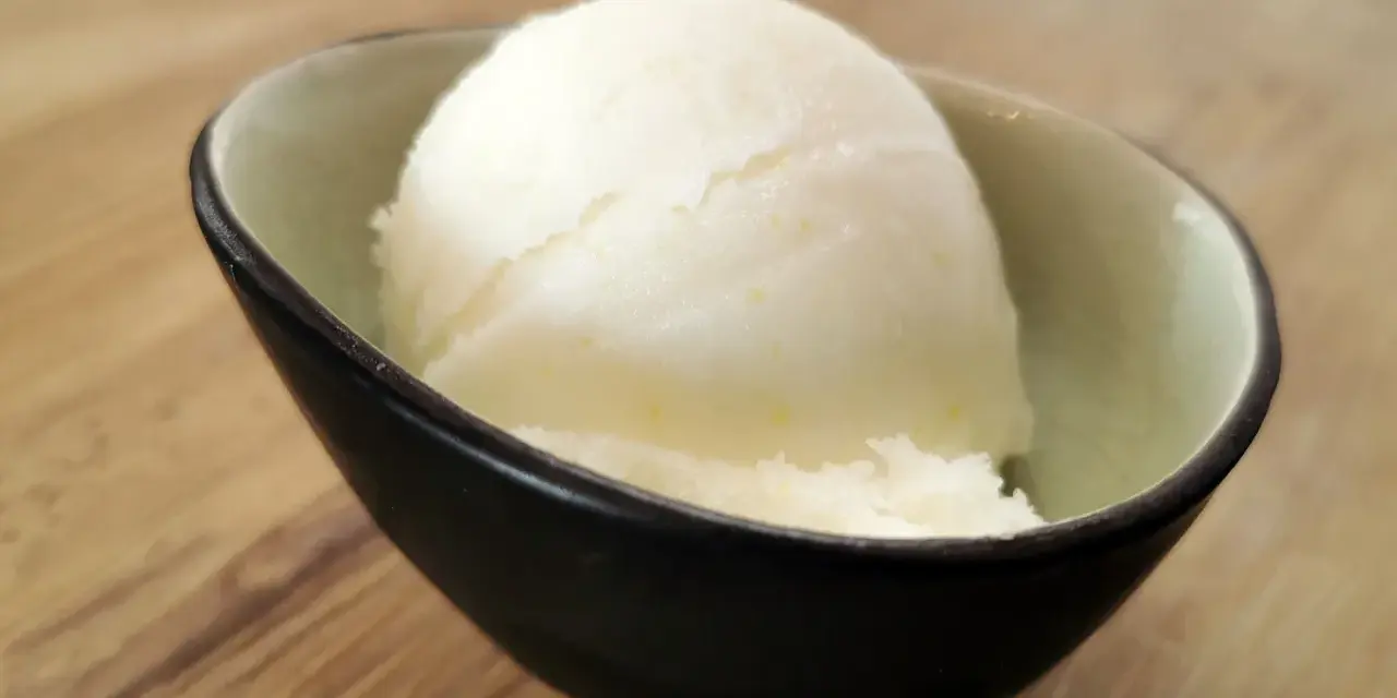 Ein Löffel cremiges Sorbet ohne Zucker in einer stilvollen Schale auf Holzhintergrund. Erfrischend und leicht.