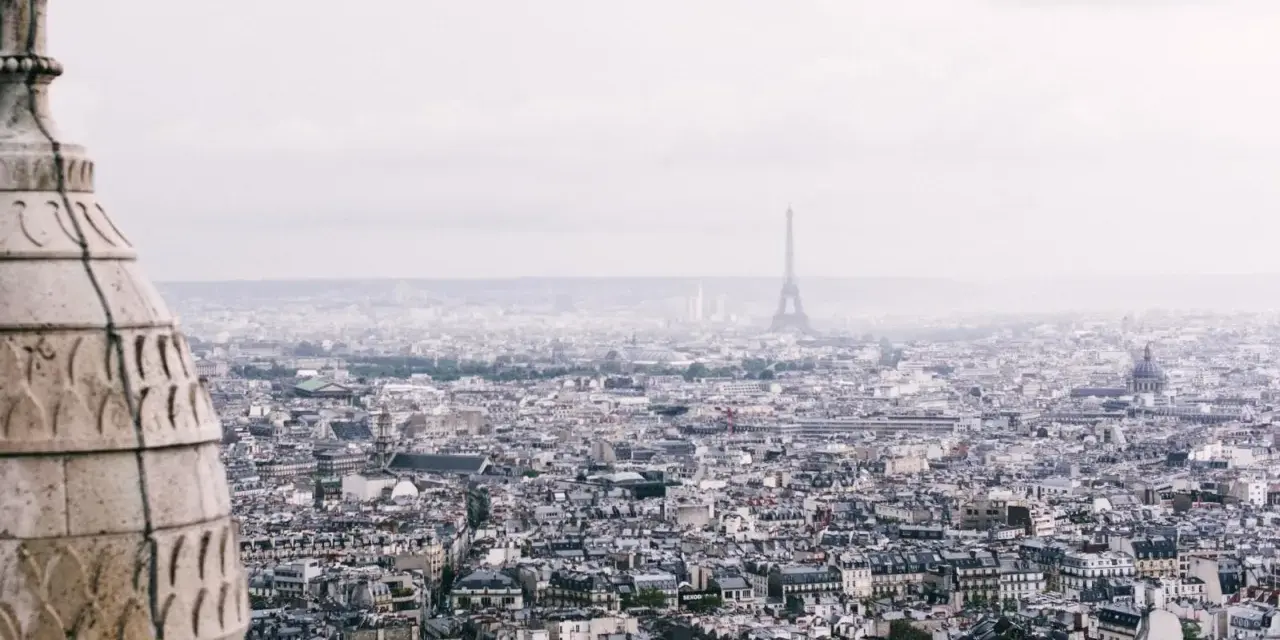 Vista panorámica de París con la Torre Eiffel al fondo. La arquitectura de la ciudad evoca un sentimiento de "enchanté significado".