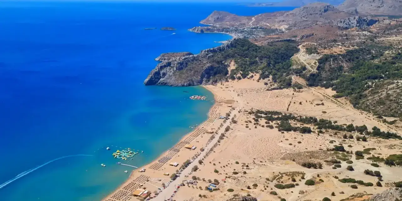 Malownicze plaże Rodos z turkusową wodą, piaszczystym wybrzeżem, leżakami i wodnym parkiem rozrywki.