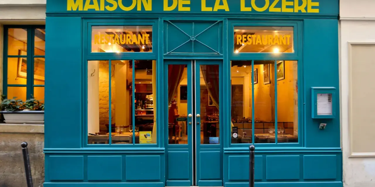 Maison de la Lozère, un ristorante accogliente dove mangiare a Parigi. L'insegna gialla risalta sulla facciata turchese.