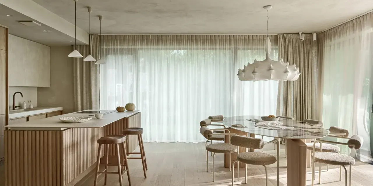 Nowoczesna kuchnia z wyspą i jadalnią. Wnętrze rozświetla designerska lampa wisząca, a całość dopełnia podwieszany sufit.