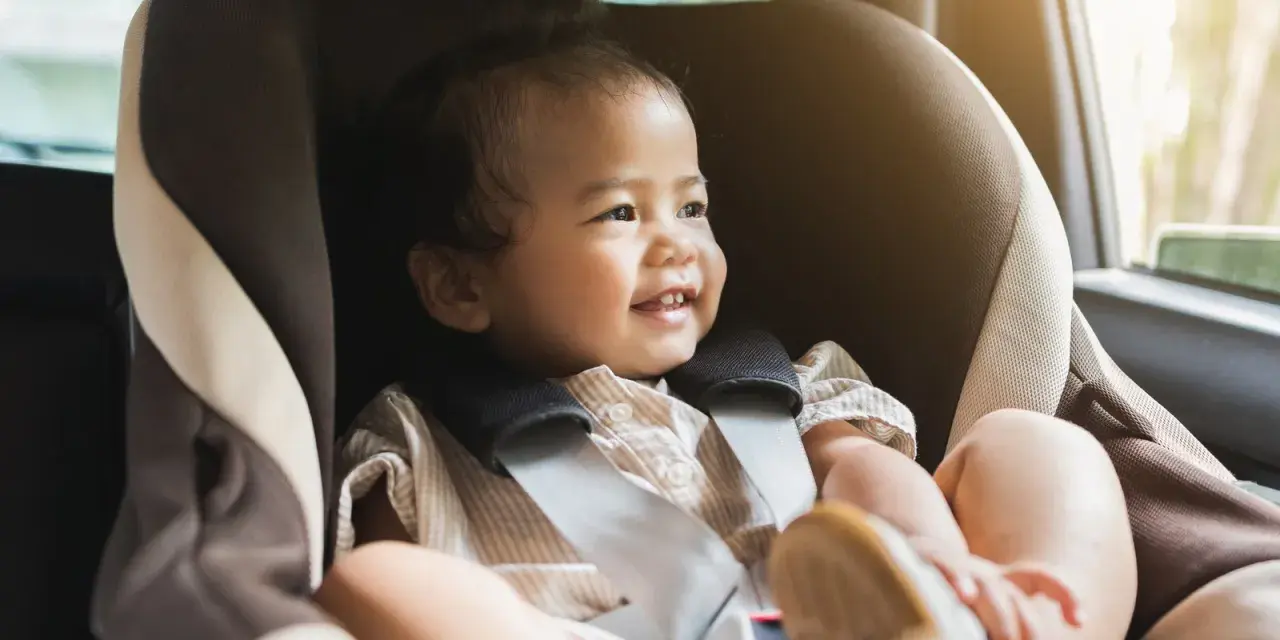 Glückliches Kleinkind im Kindersitz, bereit für eine Fahrt. Ein reboarder test zeigt, wie sicher es ist.