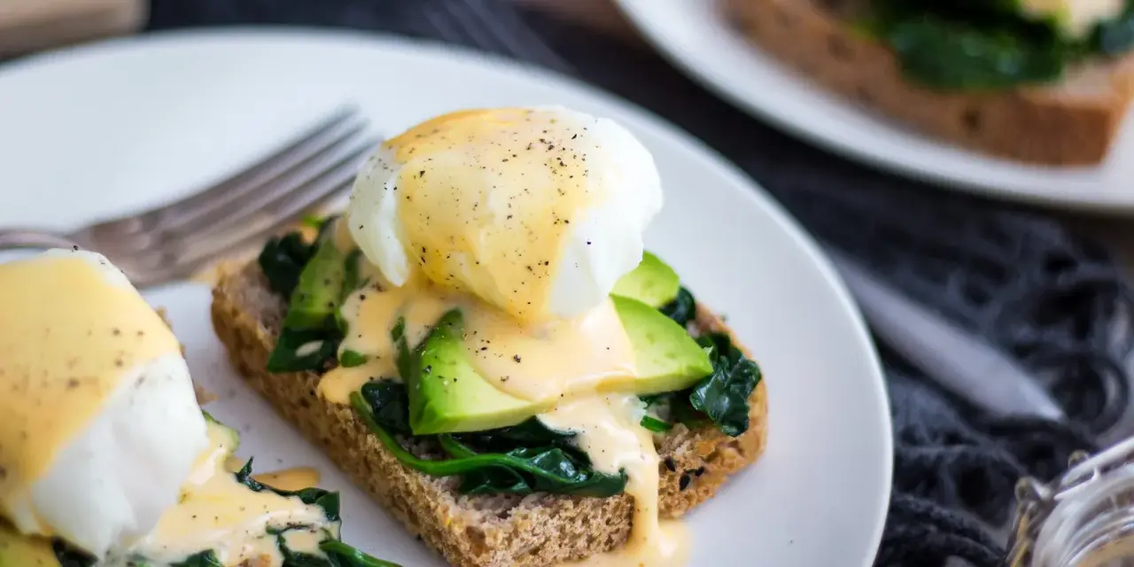 Pyszne jajka po florencku na tostach z awokado i szpinakiem, polane sosem holenderskim. Idealne na brunch!