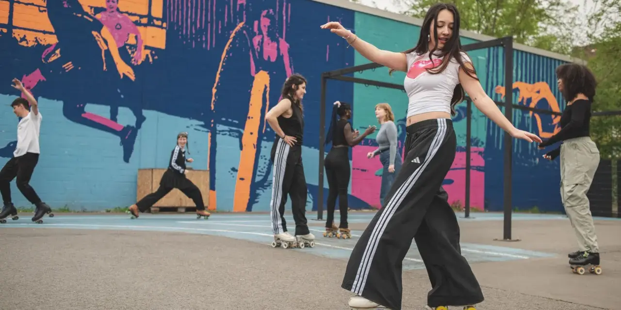 Eine Gruppe junger Leute genießt das Roller-Skating in Berlin vor einer bunten Wandmalerei.