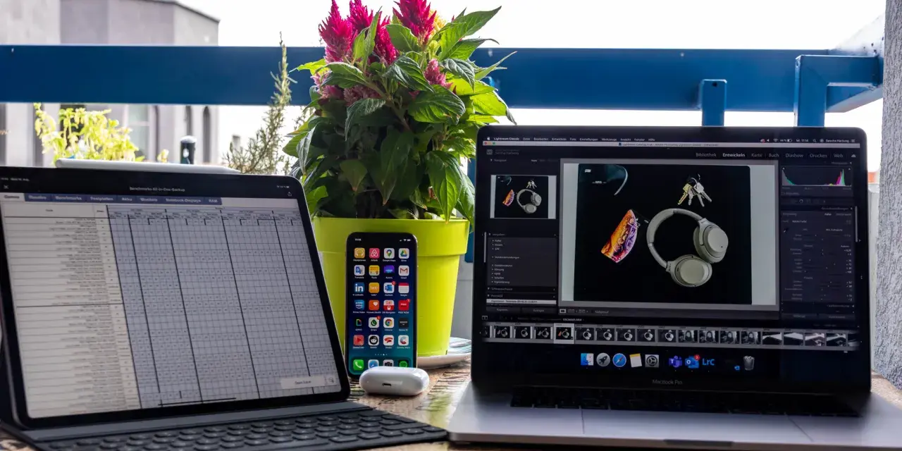 iPad Pro mit Tastatur, iPhone, AirPods und MacBook Pro mit Kopfhörern und Schlüsseln.